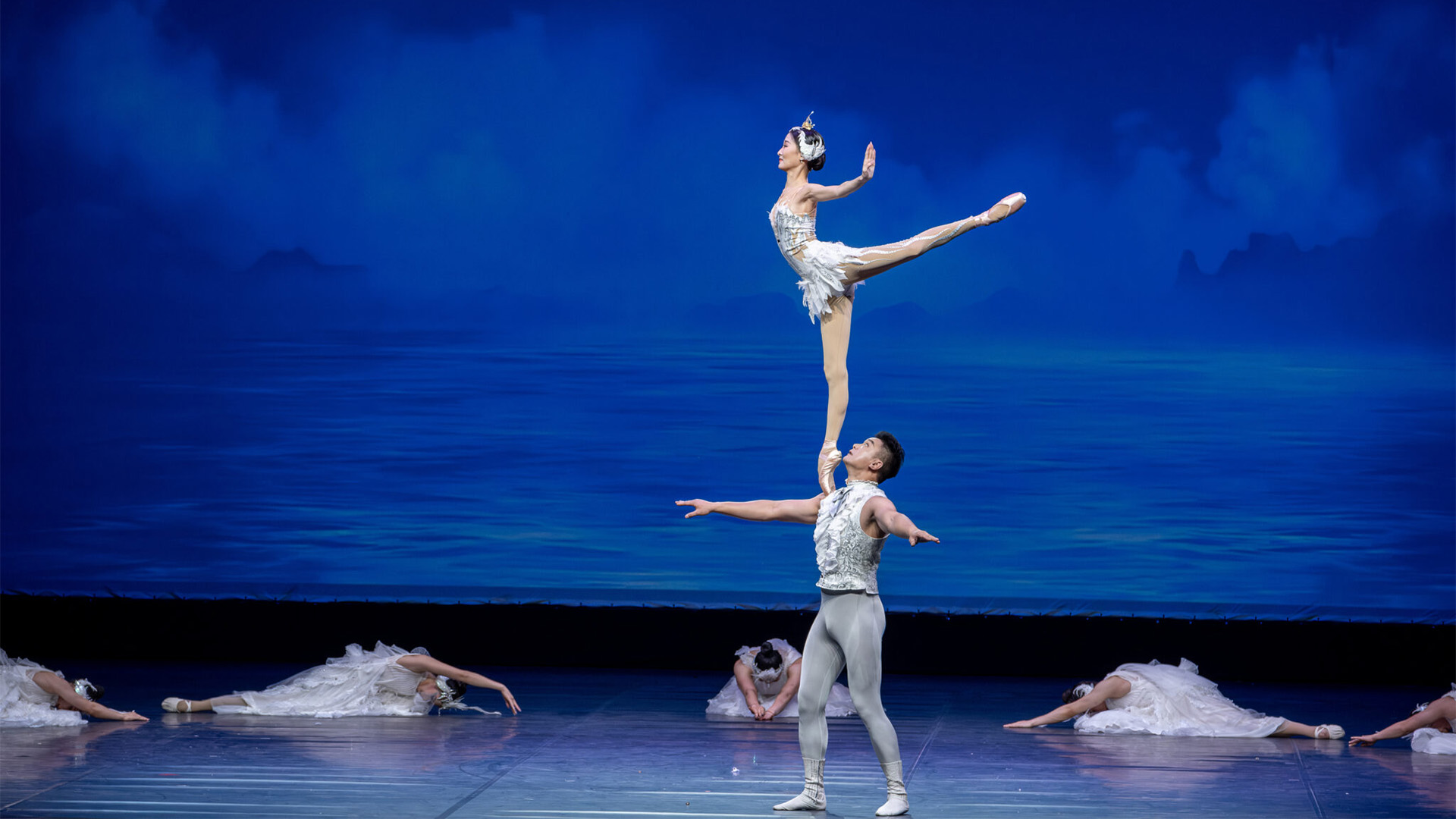 Ballerina balances en pointe on a male dancer’s arm during Guangzhou Acrobatic Troupe’s 2024 performance, symbolizing trust, balance, and mutual support among artists.